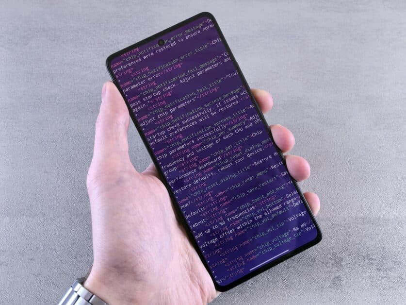 Vue rapprochée d'un smartphone affichant des lignes de code source de configuration, illustrant l'aspect technique de la création d'application mobile.