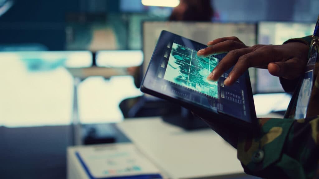 Professionnel consultant une interface de données complexe sur tablette dans un centre de pilotage numérique