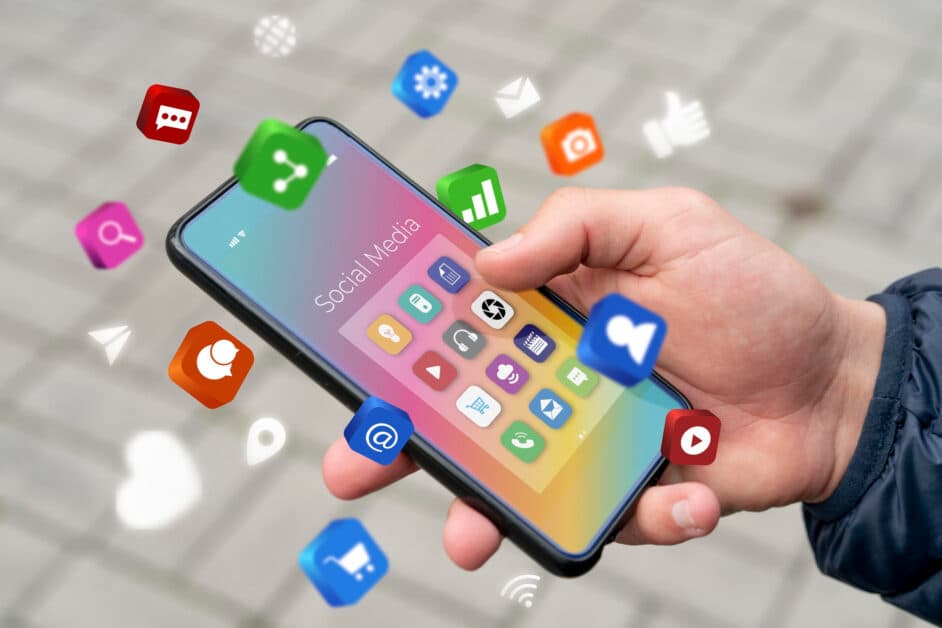 Main tenant un smartphone avec icônes d'applications mobiles illustrant la diversité des fonctionnalités et leur coût de développement