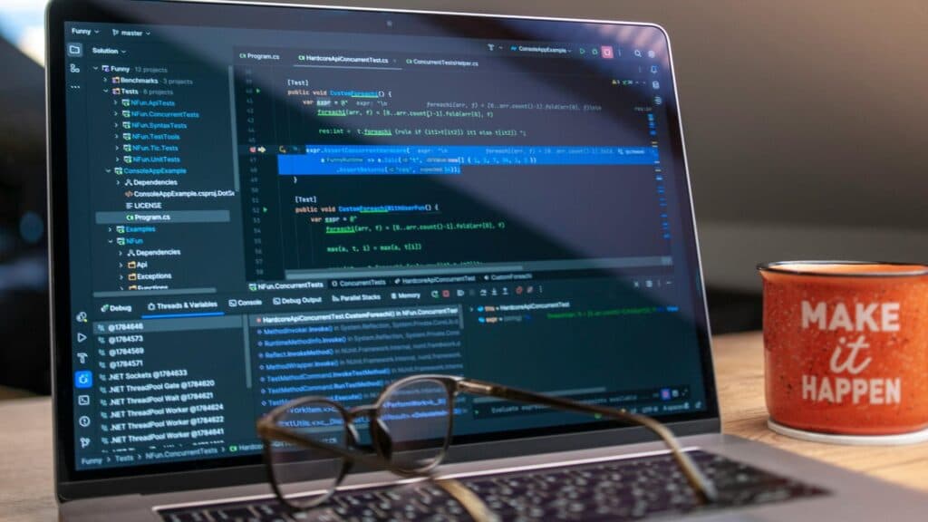 Session de debug en .NET sur laptop avec mug Make it happen illustrant la rigueur technique d'une équipe Scrum