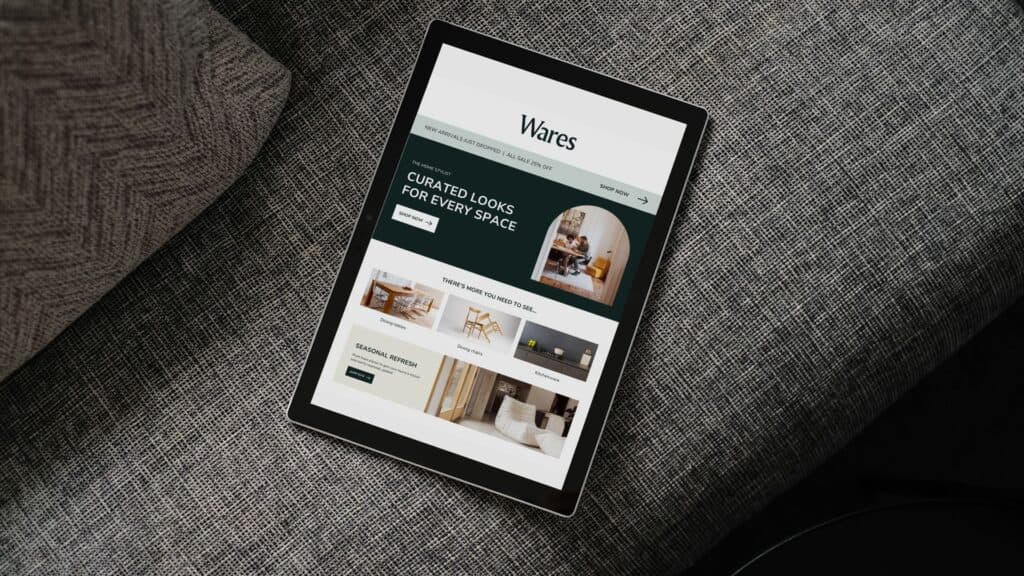 Tablette numérique affichant un site de décoration d'intérieur posée sur le coussin d'un canapé gris texturé